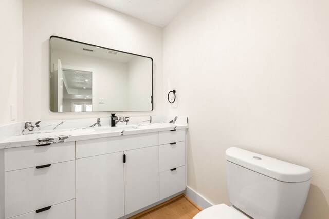 bathroom featuring baseboards, vanity, toilet, and wood finished floors