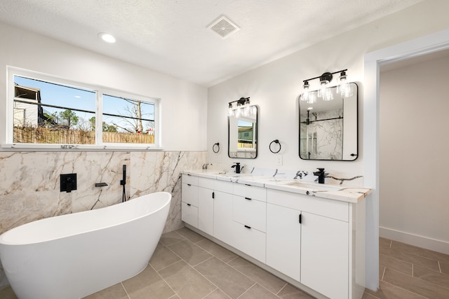 full bath featuring double vanity, a soaking tub, visible vents, and a sink