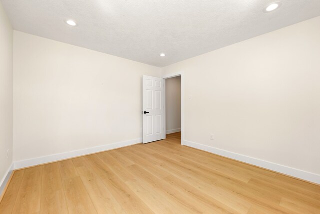 unfurnished room featuring light wood-type flooring, baseboards, a textured ceiling, and recessed lighting