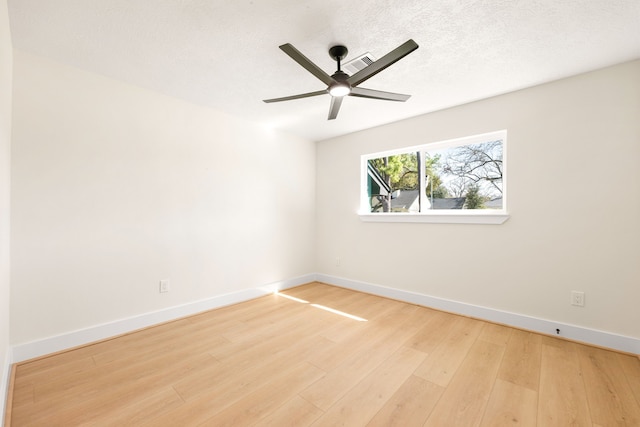 empty room with a textured ceiling, wood finished floors, visible vents, a ceiling fan, and baseboards