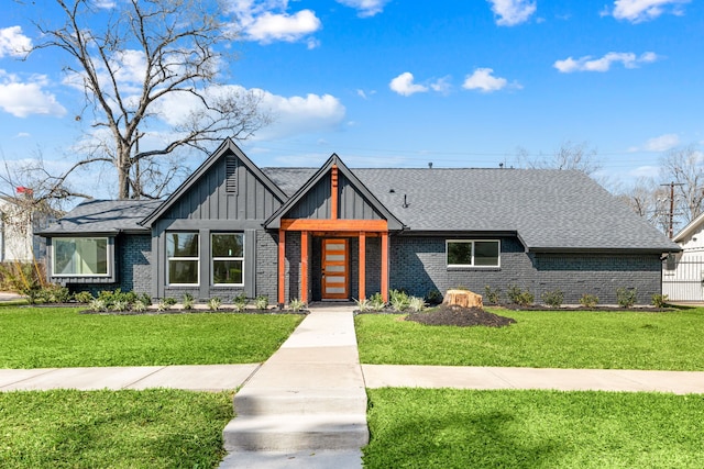 view of front of home featuring a front lawn, board and batten siding, a shingled roof, and brick siding