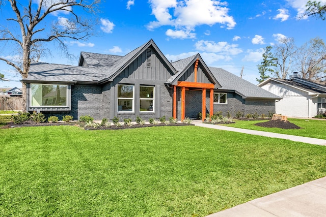 view of front of house with a front lawn, board and batten siding, a shingled roof, and brick siding