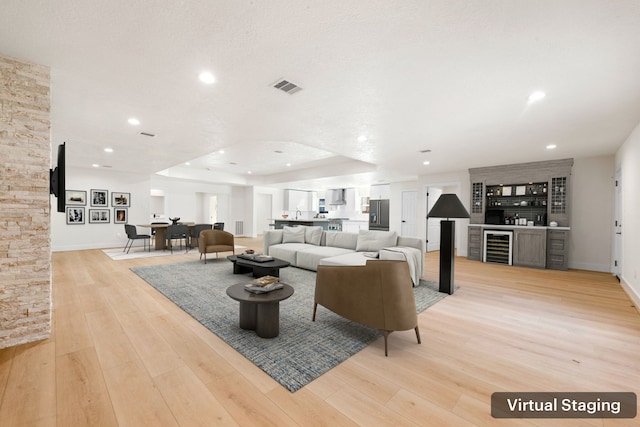 living room featuring recessed lighting, beverage cooler, visible vents, light wood-type flooring, and a dry bar