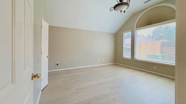 spare room with lofted ceiling, baseboards, visible vents, and light wood finished floors