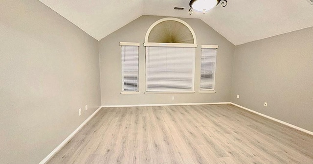 unfurnished room featuring lofted ceiling, visible vents, baseboards, and wood finished floors