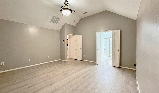 unfurnished bedroom featuring lofted ceiling, baseboards, visible vents, and wood finished floors