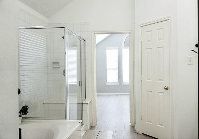 bathroom with lofted ceiling, a garden tub, a shower stall, and wood finished floors