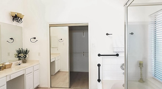 full bathroom featuring a shower with door, a bathtub, wood finished floors, and vanity