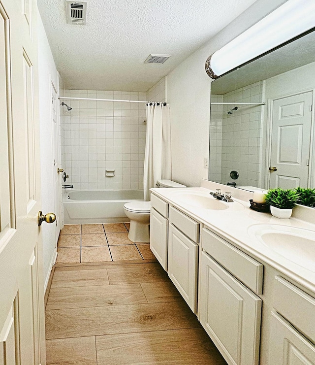 full bathroom featuring visible vents, toilet, a sink, a textured ceiling, and wood finished floors