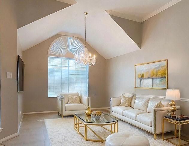 living room featuring lofted ceiling, an inviting chandelier, and baseboards