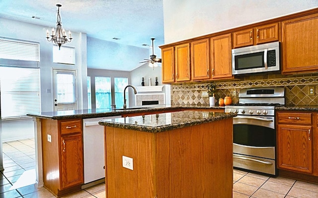 kitchen featuring light tile patterned floors, stainless steel appliances, brown cabinetry, a kitchen island, and a peninsula