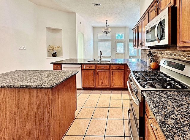 kitchen featuring light tile patterned floors, stainless steel appliances, a peninsula, a sink, and visible vents