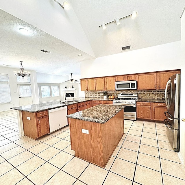 kitchen featuring appliances with stainless steel finishes, light tile patterned flooring, a sink, and a peninsula