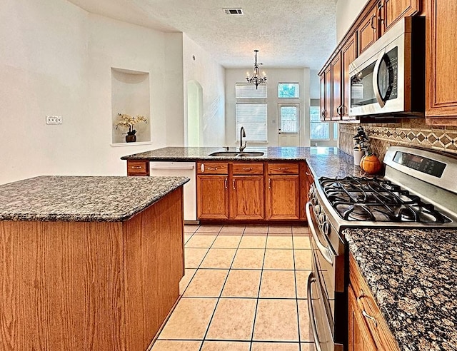 kitchen featuring light tile patterned floors, stainless steel appliances, visible vents, a sink, and a peninsula