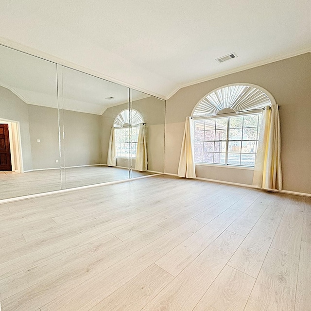 spare room featuring crown molding, visible vents, vaulted ceiling, and wood finished floors