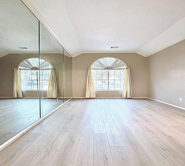 spare room featuring plenty of natural light, visible vents, vaulted ceiling, and wood finished floors