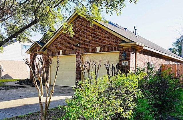 view of home's exterior featuring driveway, brick siding, and an attached garage