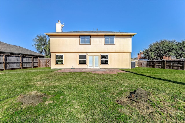 rear view of property featuring a patio area, a fenced backyard, a chimney, and a lawn