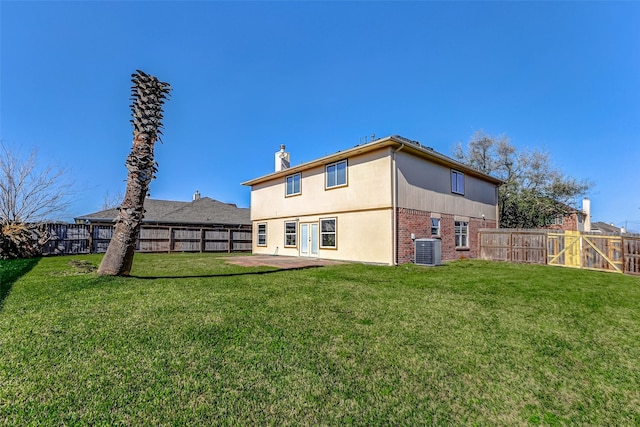 rear view of property with a fenced backyard, a lawn, central AC, and brick siding