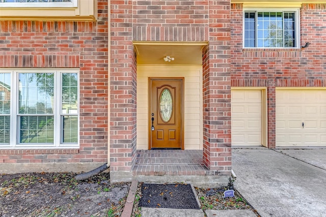 view of exterior entry featuring brick siding and an attached garage