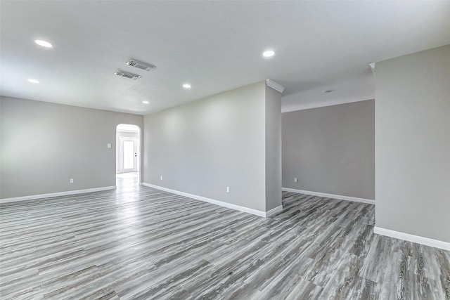 spare room with visible vents, arched walkways, baseboards, wood finished floors, and recessed lighting