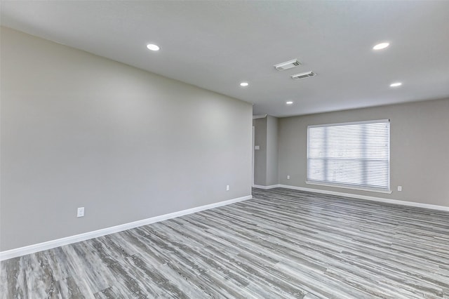 empty room featuring baseboards, visible vents, wood finished floors, and recessed lighting