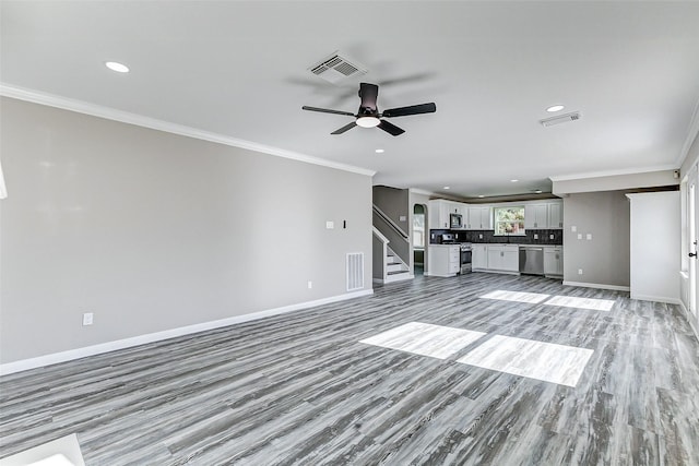 unfurnished living room featuring ornamental molding, visible vents, and baseboards