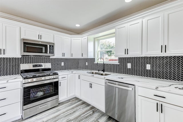 kitchen with white cabinets, backsplash, stainless steel appliances, and a sink