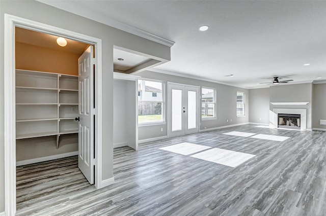 unfurnished living room featuring a fireplace, baseboards, wood finished floors, and french doors