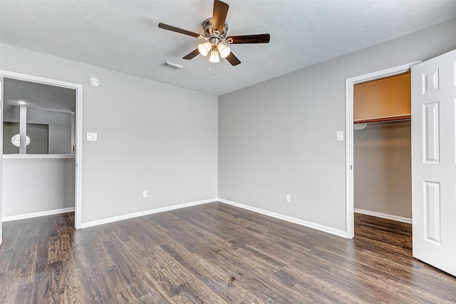 unfurnished bedroom with baseboards, a spacious closet, visible vents, and wood finished floors