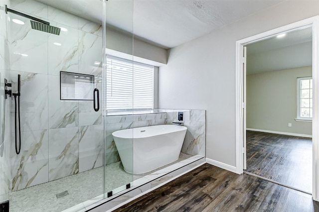 bathroom featuring a soaking tub, a marble finish shower, baseboards, and wood finished floors