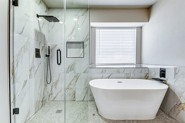 bathroom featuring a freestanding tub, a marble finish shower, and tile walls