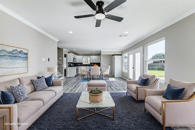 living room with french doors, crown molding, recessed lighting, visible vents, and light wood-style flooring