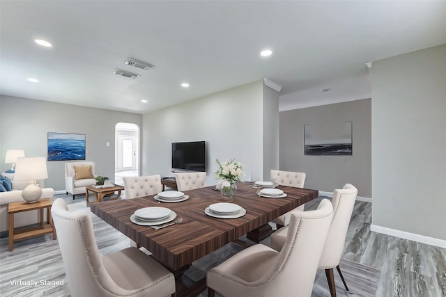 dining room featuring arched walkways, light wood-style flooring, recessed lighting, visible vents, and baseboards