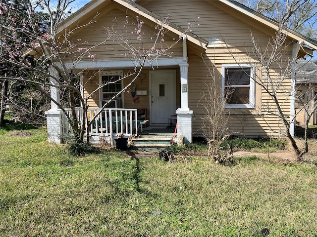 bungalow featuring covered porch and a front lawn