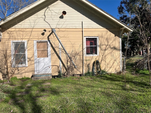 back of property with entry steps, a lawn, and fence