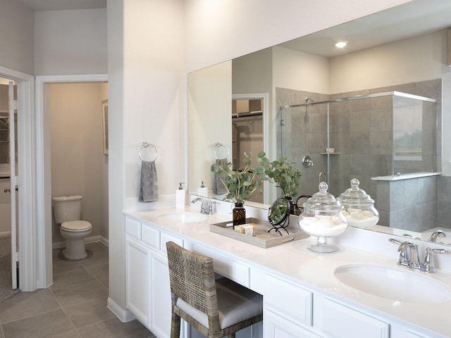 full bathroom featuring a stall shower, a sink, a walk in closet, and tile patterned floors