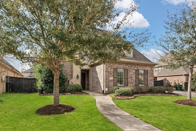 view of front of property with roof with shingles, fence, a front lawn, and brick siding