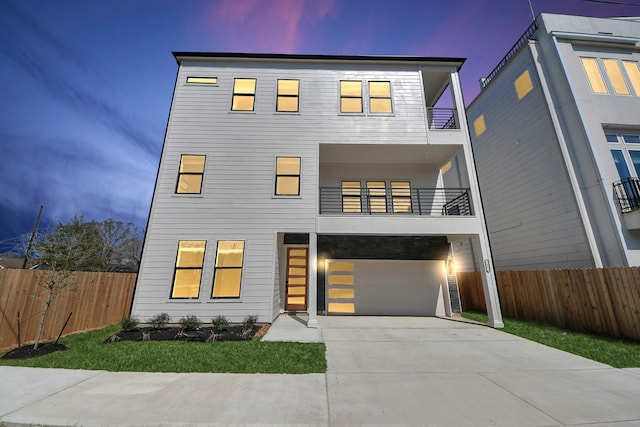 contemporary home with a garage, driveway, fence, and a balcony