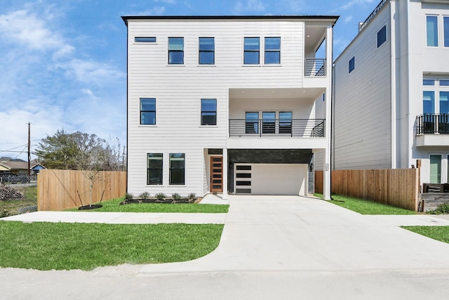 view of front of property with a balcony, an attached garage, fence, and concrete driveway