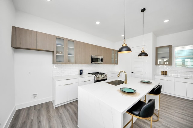 kitchen with glass insert cabinets, modern cabinets, appliances with stainless steel finishes, and a sink