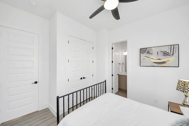 bedroom with ceiling fan, connected bathroom, wood finished floors, baseboards, and a closet