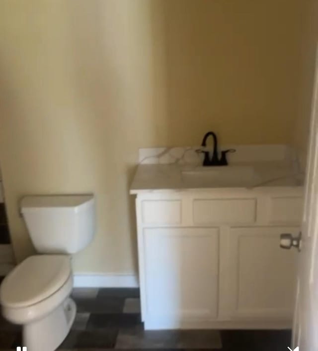 bathroom with baseboards, vanity, and toilet