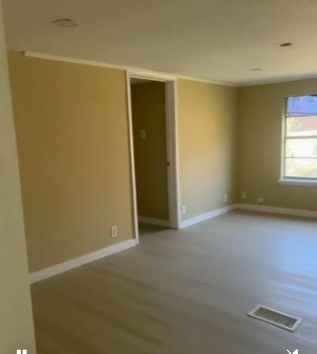 empty room with baseboards, visible vents, and wood finished floors