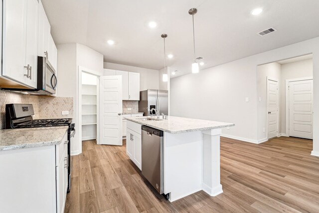 2542 Bay Winds Ln, Baytown, TX 77523 - kitchen with stainless steel appliances, light wood-style floors, tasteful backsplash, white cabinets, and recessed lighting