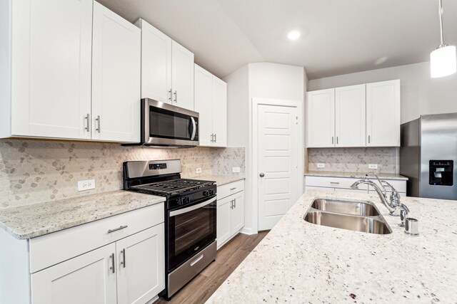 2542 Bay Winds Ln, Baytown, TX 77523 - kitchen featuring stainless steel appliances, a sink, wood finished floors, white cabinetry, and light stone countertops