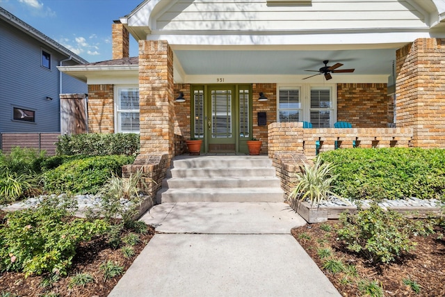 property entrance featuring covered porch, brick siding, a chimney, and a ceiling fan