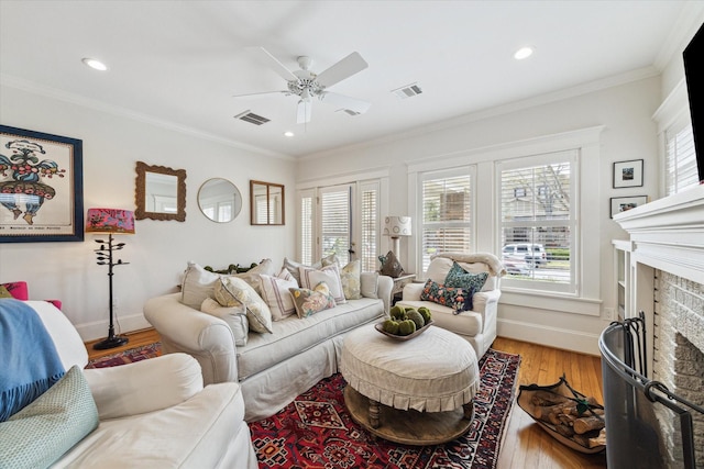 living room featuring plenty of natural light, ornamental molding, a fireplace, and visible vents