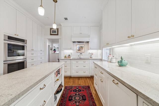 kitchen featuring double oven, premium range hood, visible vents, and white cabinets