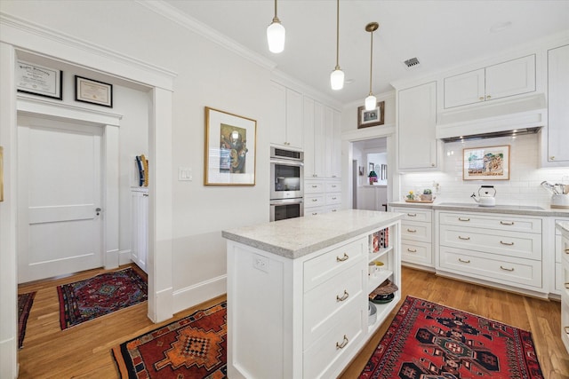 kitchen featuring light wood finished floors, tasteful backsplash, visible vents, under cabinet range hood, and double oven